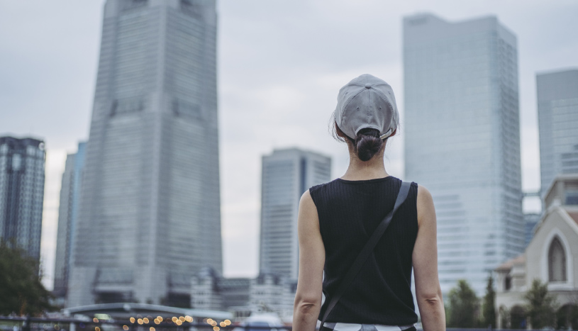 都会の街中に佇む女性の写真